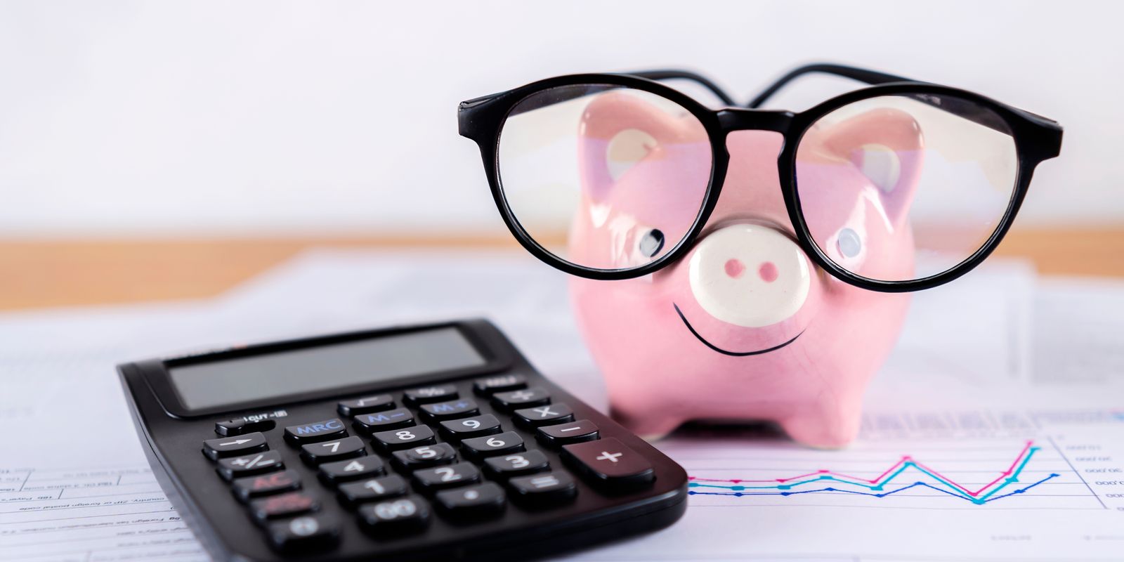 A piggy bank wearing glasses next to a calculator